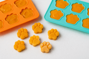 Frozen pumpkin yogurt bites for dogs in paw-shaped silicone molds.